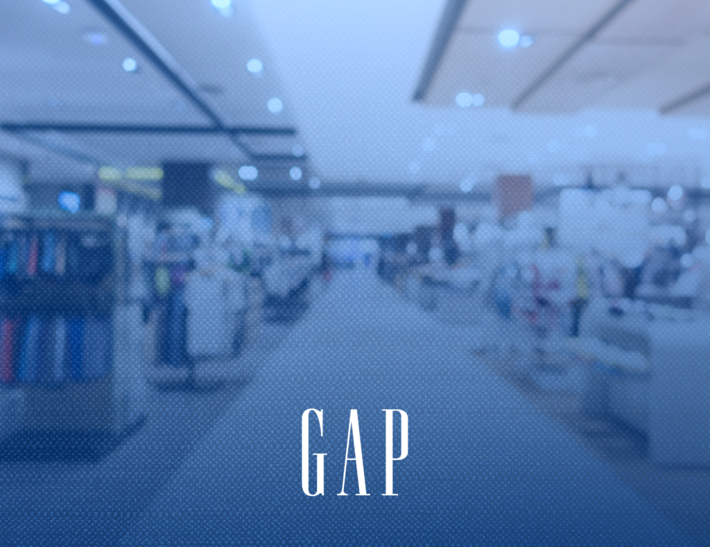 A composition showing an intentionally blurred blue-tinted clothing retail store interior environment with the clean white serif logo typography reading GAP centered at the bottom.